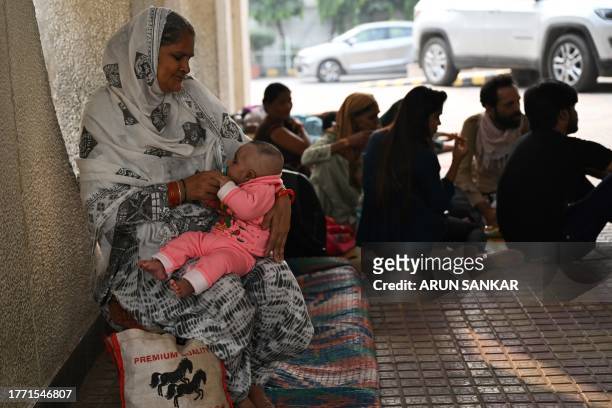 In this picture taken on November 7 a woman holds a child as they wait for treatment outside the government-run Chacha Nehru Bal Chikitsalaya...