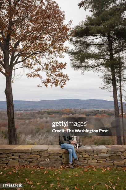 Author Chris Bohjalian sits on a rock wall with his dog, Jesse.