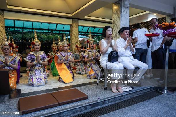 Chinese tourist prays in front of Thai dancers performing to worship Lord Brahma, during a religious ceremony to worship the Lord Brahma statue to...