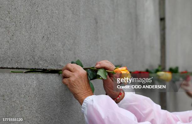 Woman places a rose in the wall during festivities at the Berlin Wall Memorial, a 1,5 kilometers stretch on the former border strip between East and...