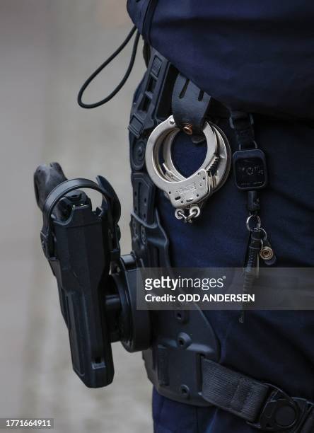 Detail of the holstered pistol, handcuffs and keys of a police officer is pictured during a commemoration for the 34th anniversary of the fall of the...