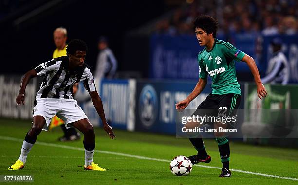 Lino of Saloniki challenges Atsuto Uchida of Schalke during the UEFA Champions League Play-off first leg match between FC Schalke 04 and PAOK...