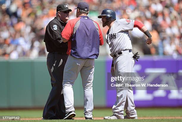 Jonny Gomes and manager John Farrell argues with second base umpire Tim Welke over Gomes being called out when coming off the base and tagged by...