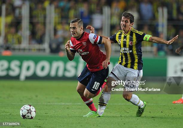 Jack Wilshere of Arsenal breaks past Emre Belozoglu of Fenerbache during the UEFA Champions League Play Off first leg match between Fenerbache SK and...