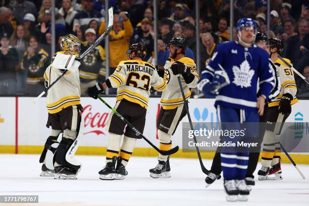 Jeremy Swayman of the Boston Bruins celebrates with teammates Brad Marchand and David Pastrnak after he saved a shot from Auston Matthews of the...