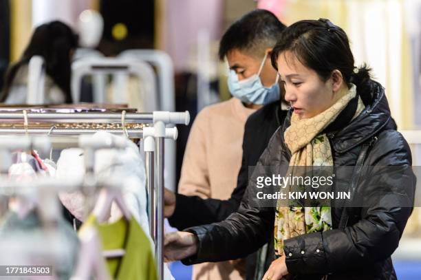 Visitors browse clothes as they attend the opening of the 2023-Autumn Garment Exhibition at the Okryu Exhibition House in Pyongyang on November 9,...