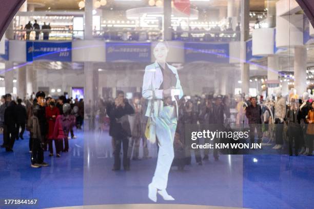 Visitors look at a digital hologram as they attend the opening of the 2023-Autumn Garment Exhibition at the Okryu Exhibition House in Pyongyang on...