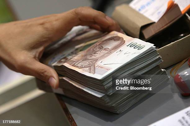 An employee handles bundles of Thai one-thousand baht banknotes at a Super Rich 1965 Co. Currency exchange store in Bangkok, Thailand, on Thursday,...