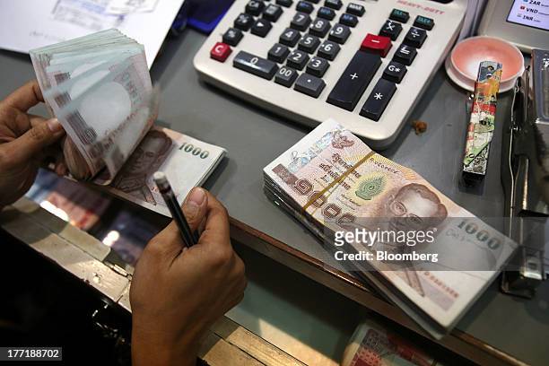 An employee handles bundles of Thai one-thousand baht banknotes at a Super Rich 1965 Co. Currency exchange store in Bangkok, Thailand, on Thursday,...