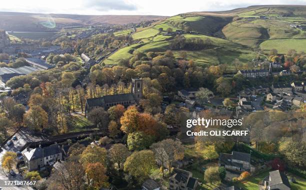 An overhead view shows deciduous trees bearing autumnal colours surrounding St Bartholomew's Church in the village of Marsden, near Huddersfield, in...