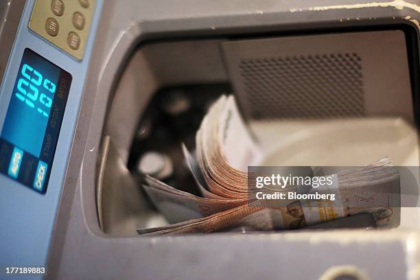 Machine counts Thai one-thousand baht banknotes at a Super Rich 1965 Co. Currency exchange store in Bangkok, Thailand, on Thursday, Aug. 22, 2013....