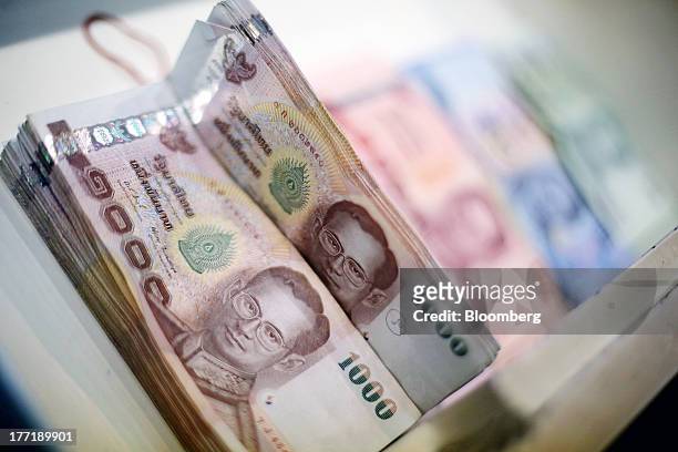 Thai baht banknotes of various denominations sit inside a drawer for an arranged photograph at a Super Rich 1965 Co. Currency exchange store in...
