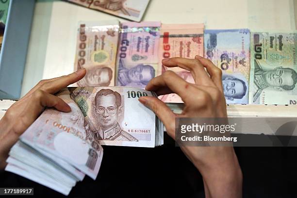 An employee counts Thai one-thousand baht banknotes as banknotes of other denominations sit inside a drawer at a Super Rich 1965 Co. Currency...