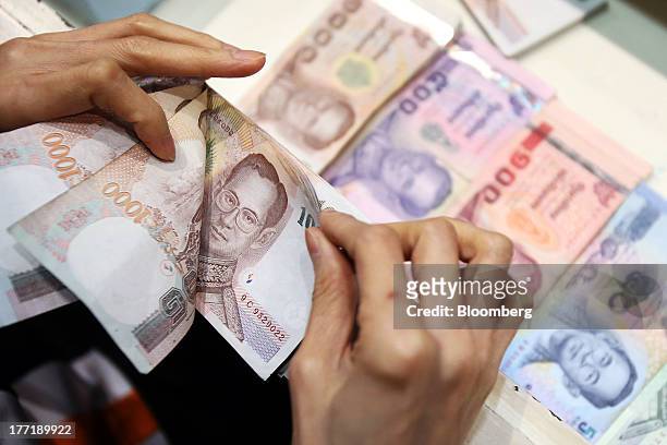 An employee counts Thai one-thousand baht banknotes as banknotes of other denominations sit inside a drawer at a Super Rich 1965 Co. Currency...