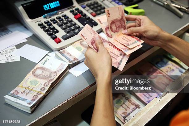 An employee handles Thai one-hundred baht banknotes as banknotes of other denominations sit inside a drawer at a Super Rich 1965 Co. Currency...