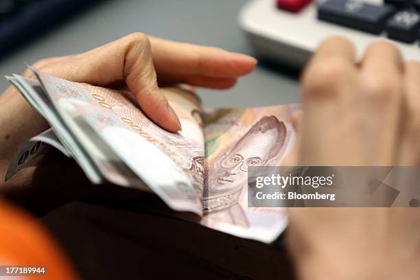 An employee counts Thai one-thousand baht banknotes at a Super Rich 1965 Co. Currency exchange store in Bangkok, Thailand, on Thursday, Aug. 22,...