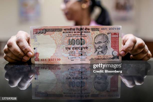 An employee displays an Indian one-thousand rupee banknote for a photograph at a branch of the HDFC Bank Ltd. In Mumbai, India on Thursday, Aug. 22,...