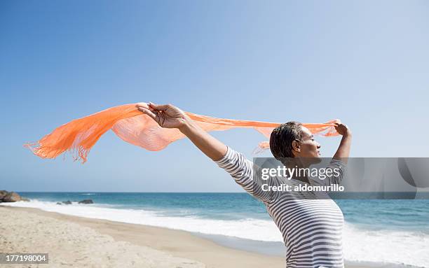 senior woman enjoying the beach - woman flying scarf stock pictures, royalty-free photos & images