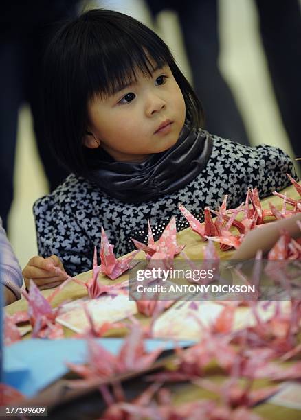 Young girl looks at origami cranes, part of 5000 that were to be folded for a donation drive for victims of the recent Japan earthquake and tsunami,...