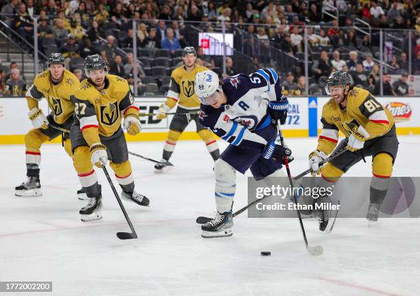 Mark Scheifele of the Winnipeg Jets skates with the puck against Shea Theodore and Jonathan Marchessault of the Vegas Golden Knights in the third...