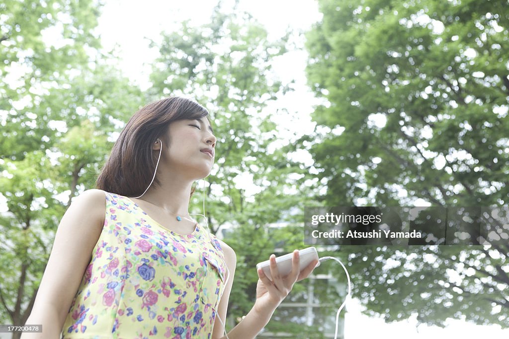 Woman listening to music in forest,closing eyes
