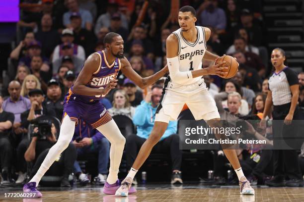 Victor Wembanyama of the San Antonio Spurs handles the ball against Kevin Durant of the Phoenix Suns during the second half of the NBA game at...