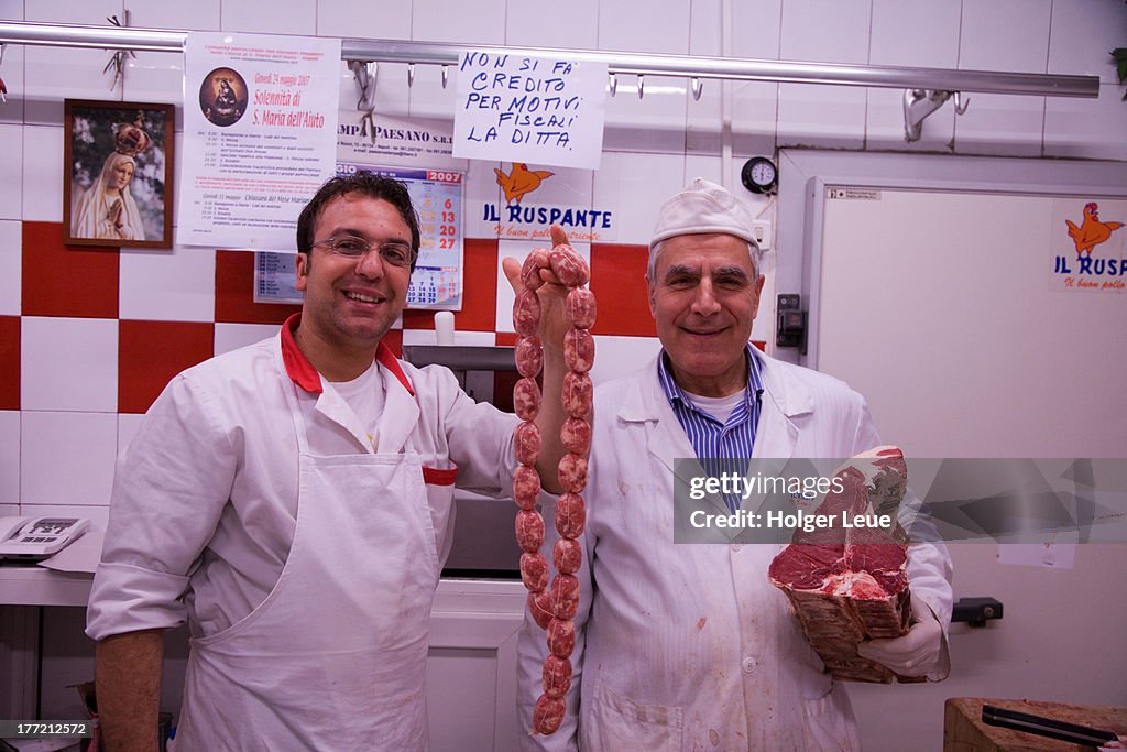 Happy butchers with sausages and meat
