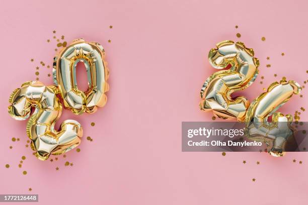 2024 new year holidays card. foil golden balloons over pink background with golden confetti - january background stock pictures, royalty-free photos & images