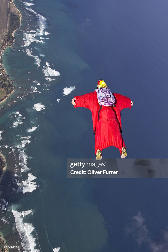 Skydiver within a wingsuit flys along the cost