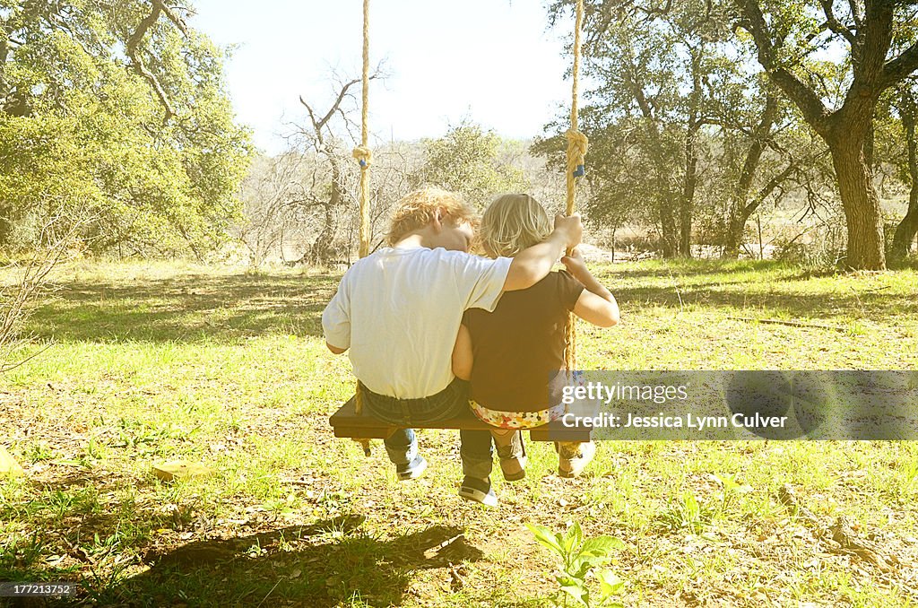 Brother and sister on a wooden swing