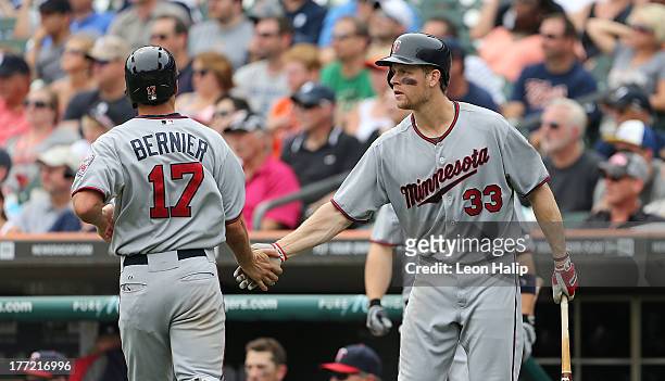 Doug Bernier of the Minnesota Twins is congratulated by Justin Morneau after scoring on the double to right center field from Chris Herrmann during...