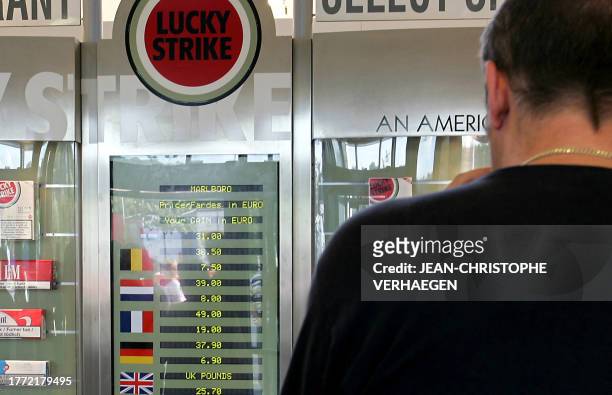 Une personne consulte le panneau d'affichage indiquant les prix des cigarettes dans divers pays européens, en les comparant à ceux pratiqués au...