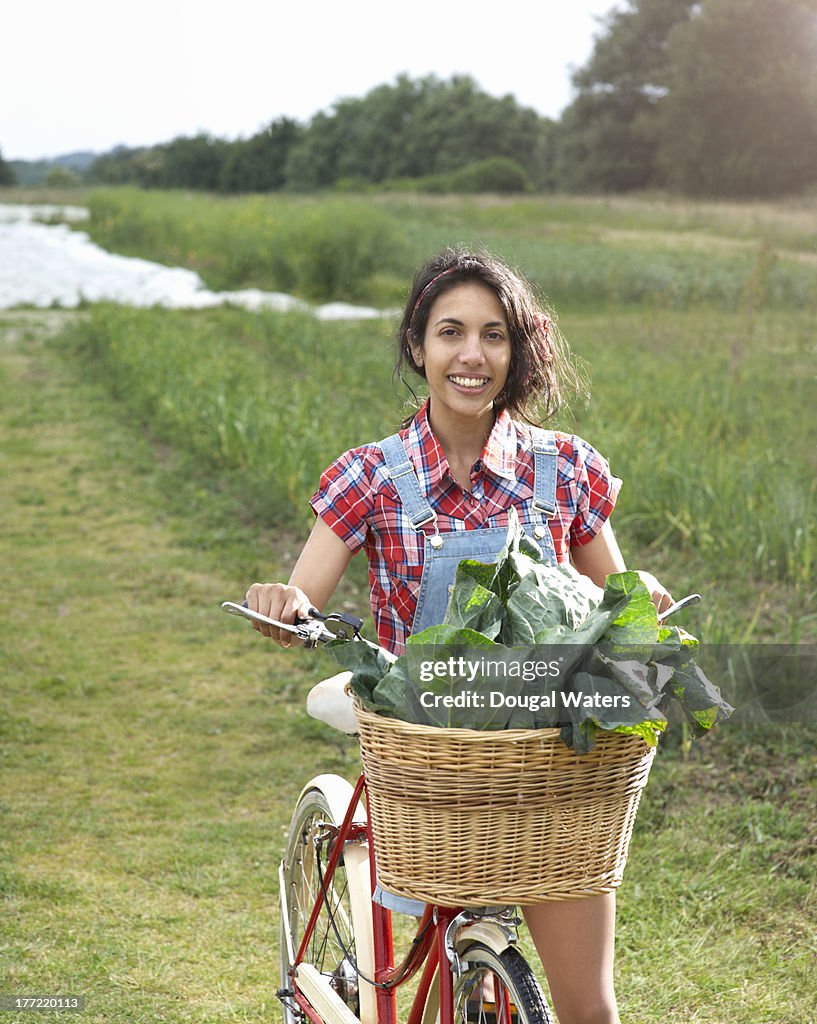 ASian woman with bicycle and fresh vegetables.