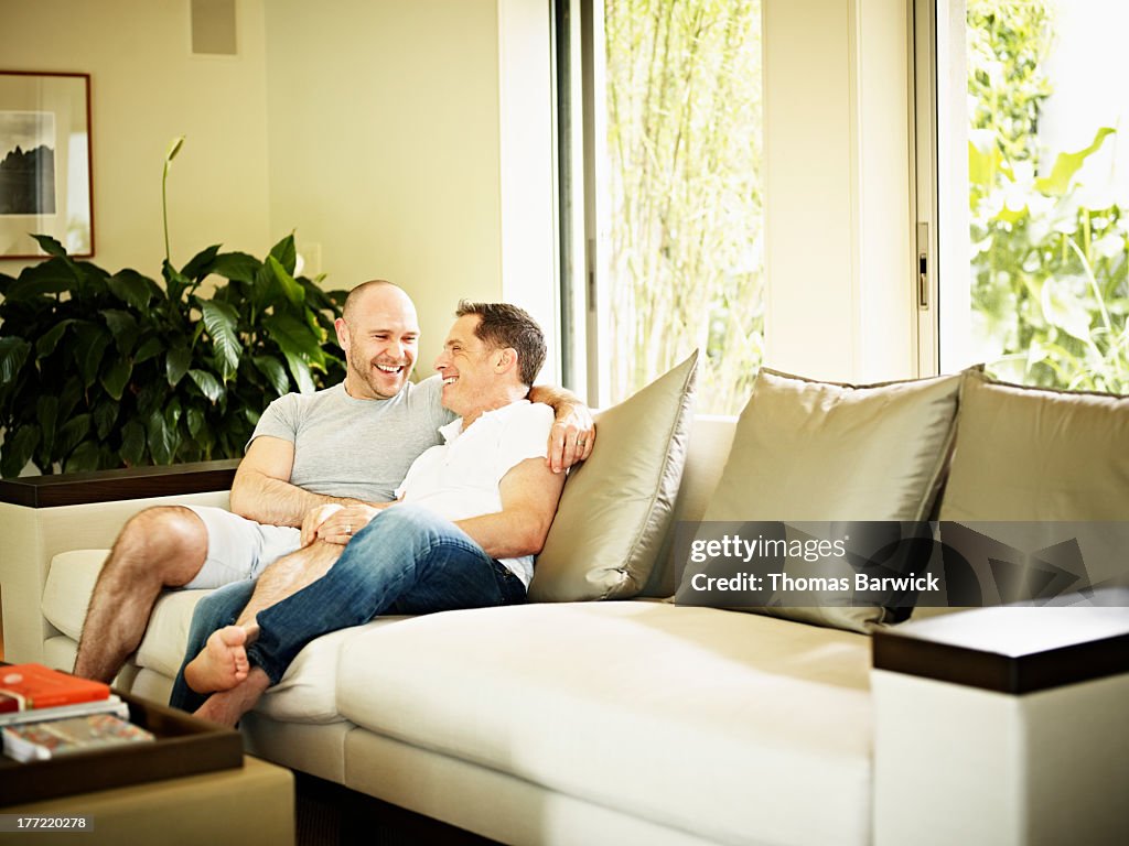 Laughing gay couple sitting together on couch