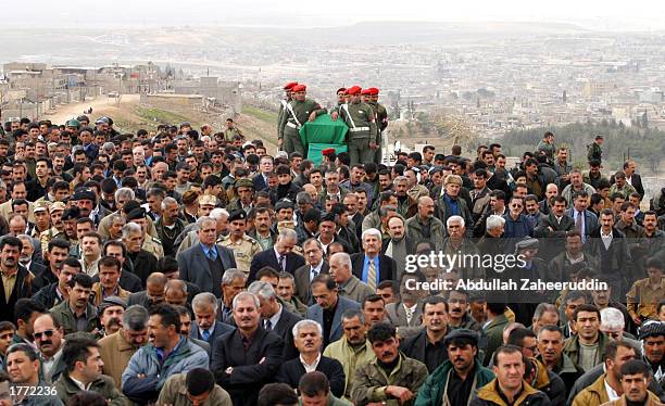 Soldiers stand near the coffin of Shukat Haji Mushir, a high ranking official of Party United Kurdistan , as mourners crowd around in a cemetery...