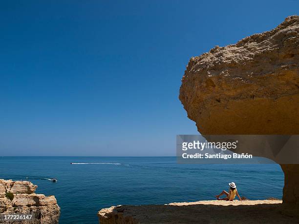 girl seating under rock looking at the sea - albufeira stock pictures, royalty-free photos & images