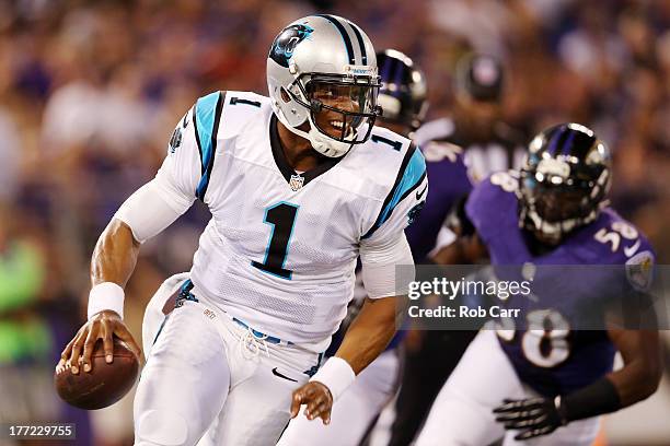 Quarterback Cam Newton of the Carolina Panthers scrambles away from linebacker Elvis Dumervil of the Baltimore Ravens during the first half of a...
