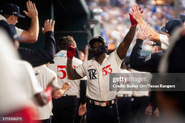 Adolis Garcia of the Texas Rangers high fives teammates in the dugout after hitting a home run during a game against the Minnesota Twins at Globe...