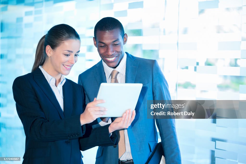 Smiling businessman and businesswoman using digital tablet