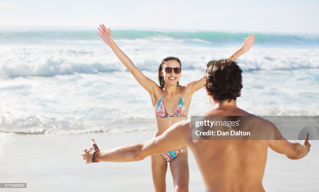 Couple with arms outstretched on beach