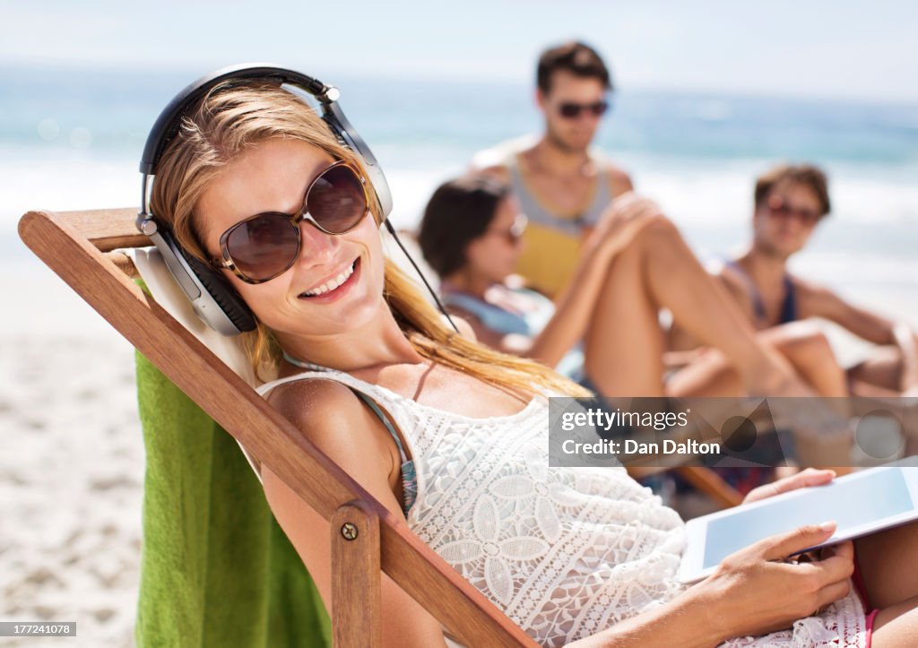 Portrait of happy woman listening to headphones at beach