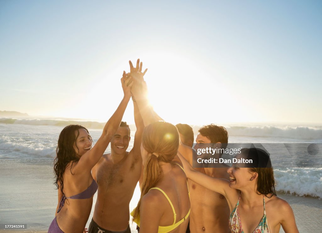 Friends high fiving in huddle at beach