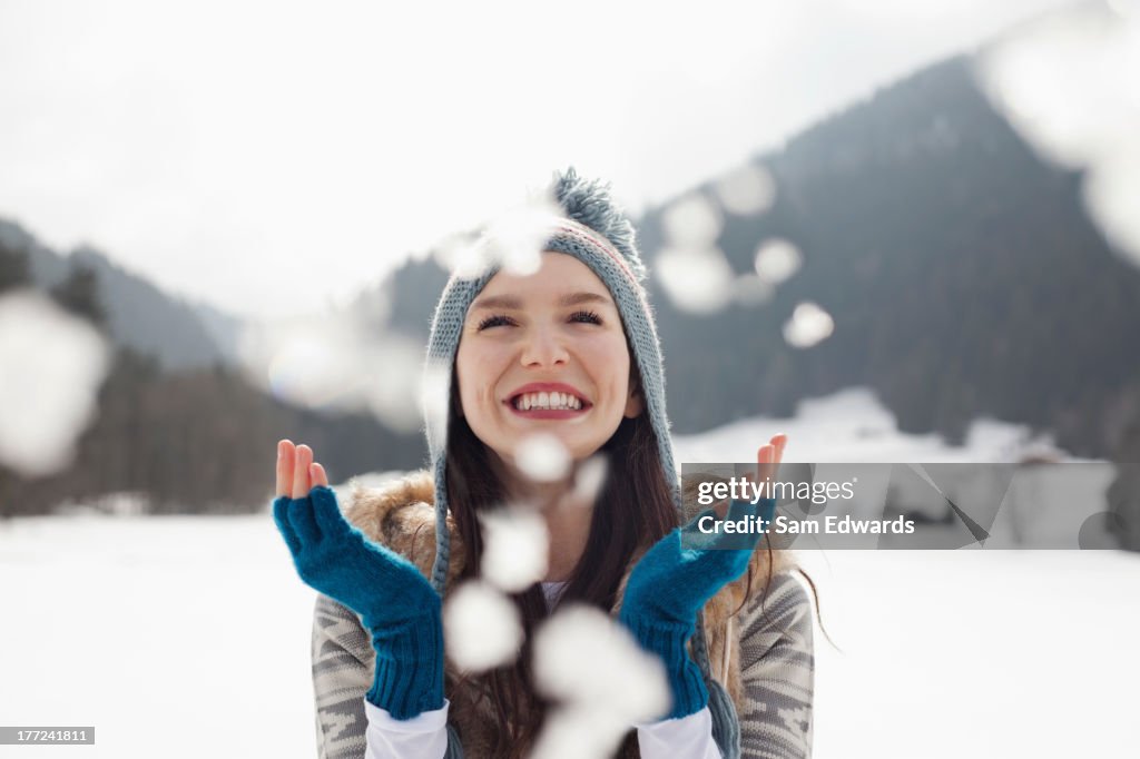 Happy woman enjoying falling snow in field