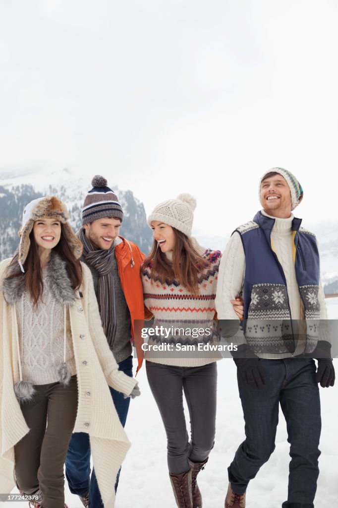 Happy friends walking in snowy field