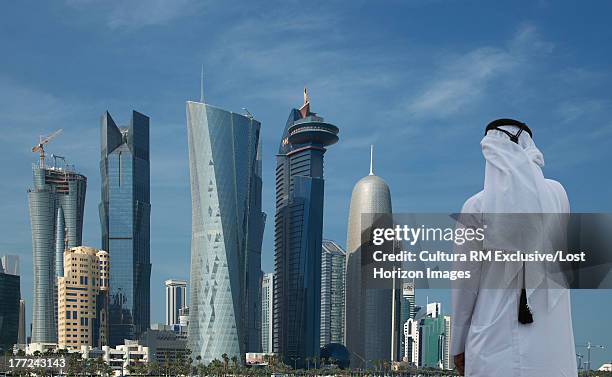 man looking at futuristic skyscrapers of downtown doha, qatar - qatar photos et images de collection