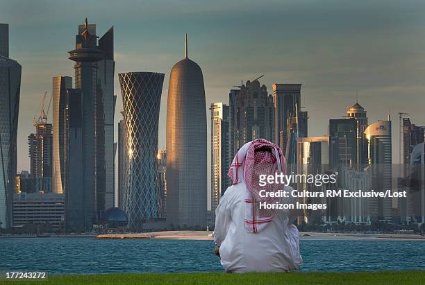 man looking at futuristic skyscrapers of downtown doha, qatar - tour of qatar fotografías e imágenes de stock