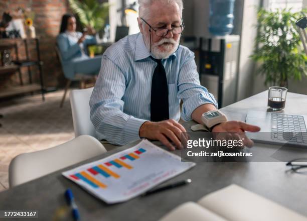 senior business man measures the pressure in the office - peripheral artery stock pictures, royalty-free photos & images