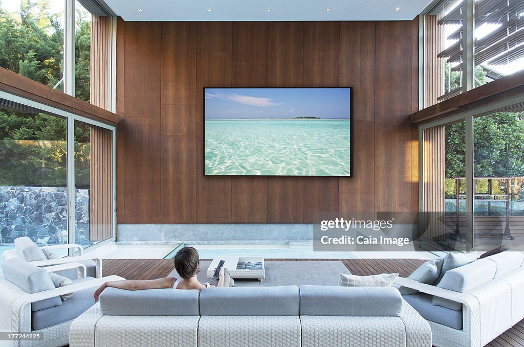 女性の大型のフラットスクリーンテレビをご覧になるには、モダンなリビングルーム