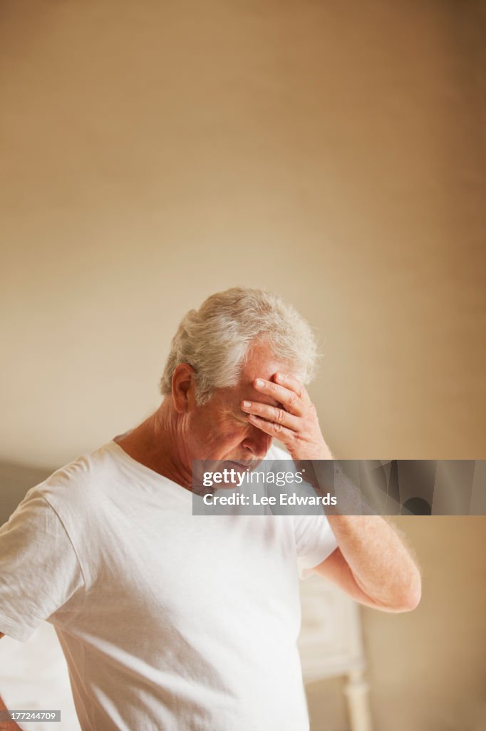 Senior hombre sosteniendo cabeza en el dolor