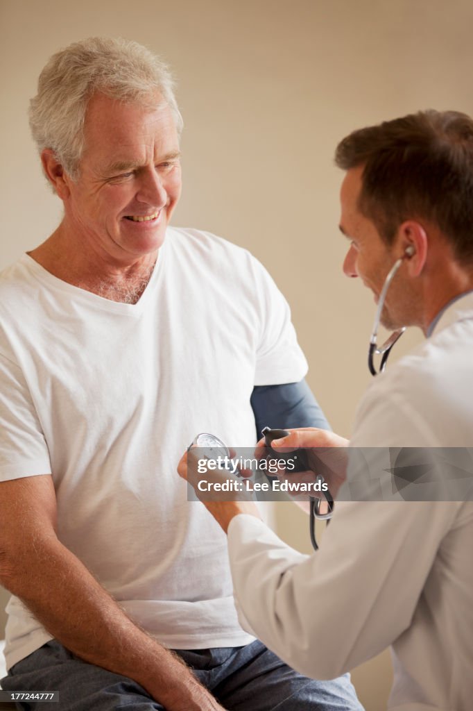 Doctor checking senior man's blood pressure in doctor's office